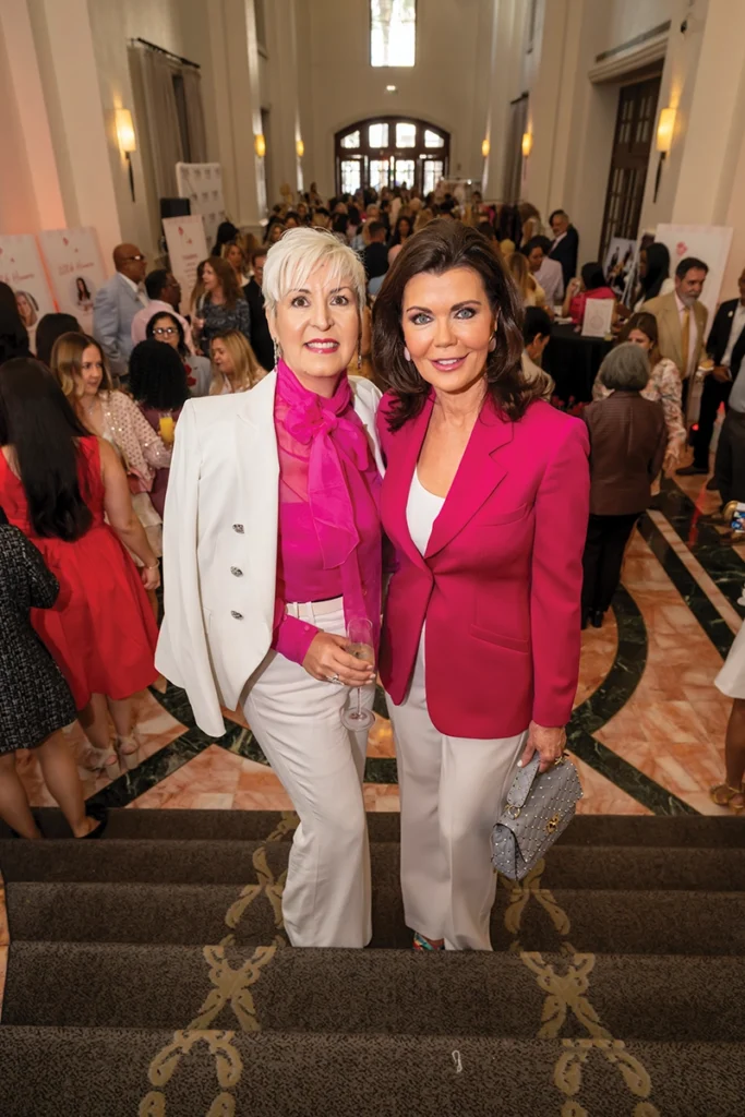 Two women on steps with crowed behind.