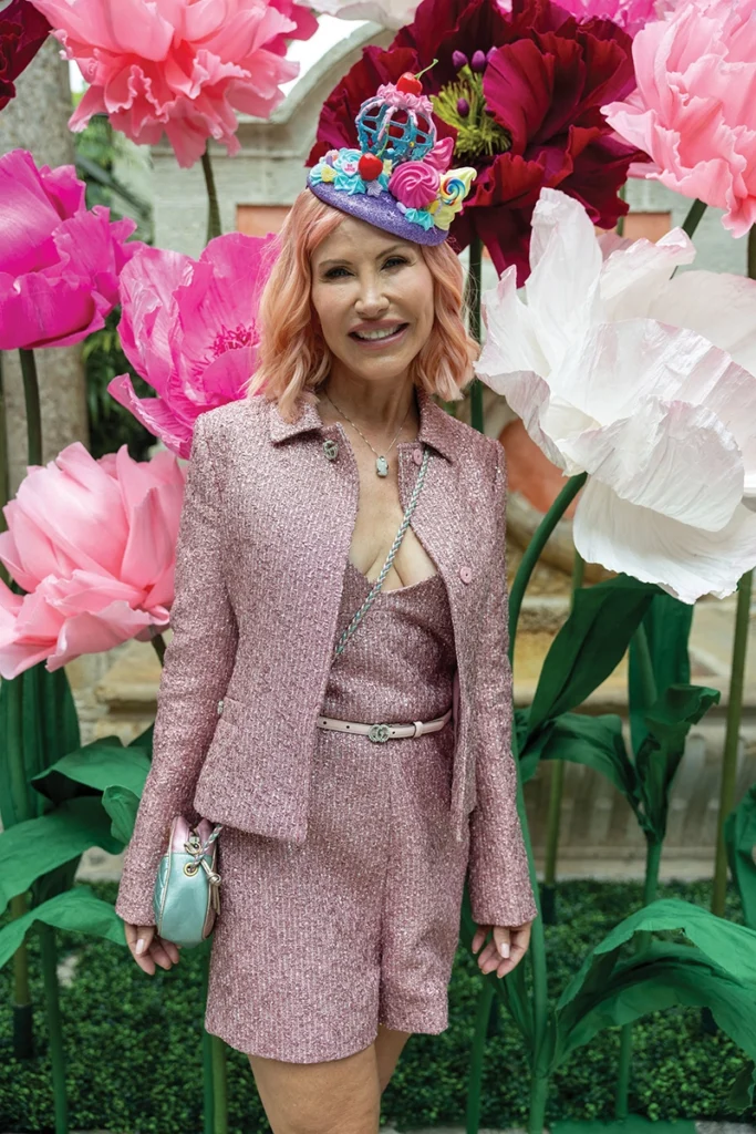 Woman in pink outfit wearing hat, smiling.