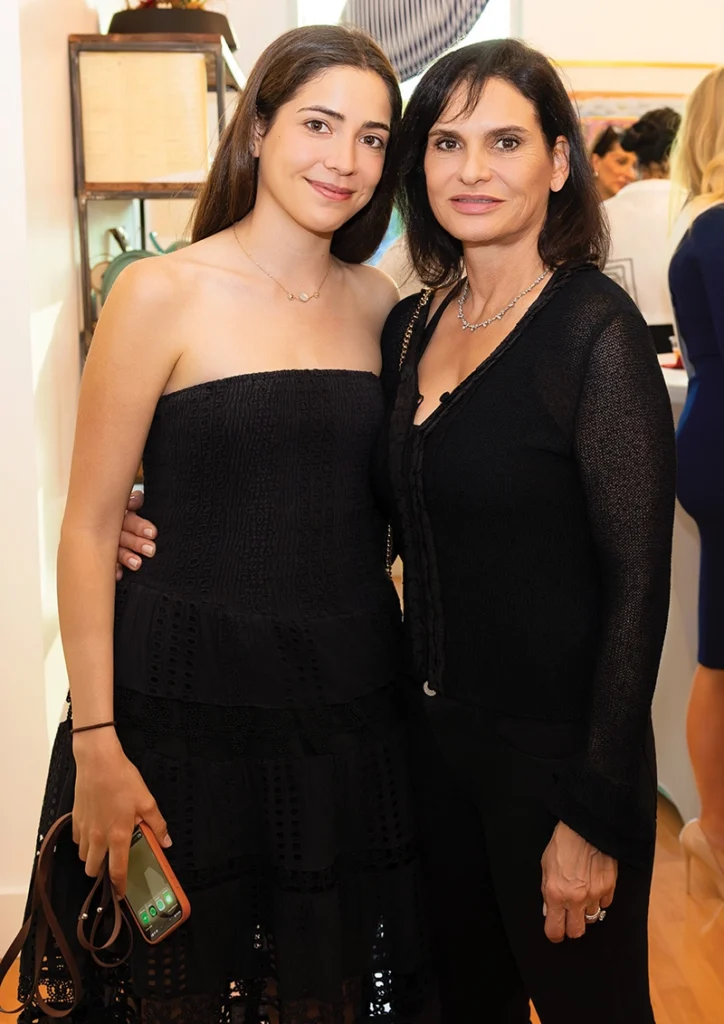 Two women in black dresses, smiling.