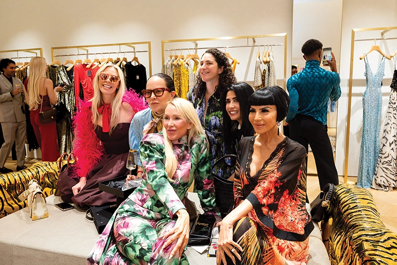 A group of women sitting together on a couch in a boutique.