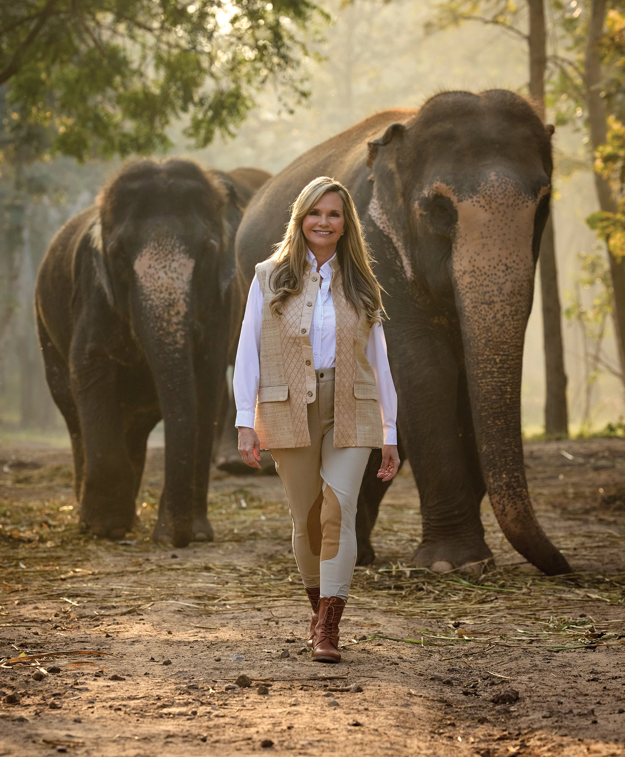 Woman walking in front of two elephants.