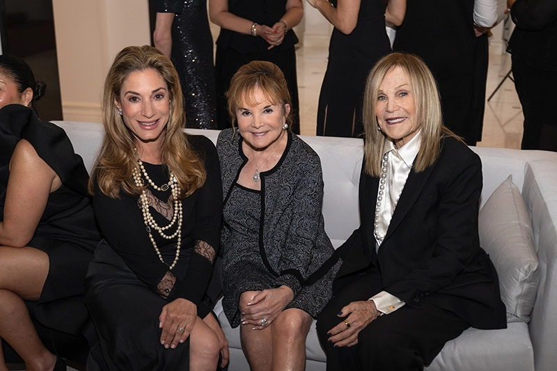 Three women sitting, smiling.