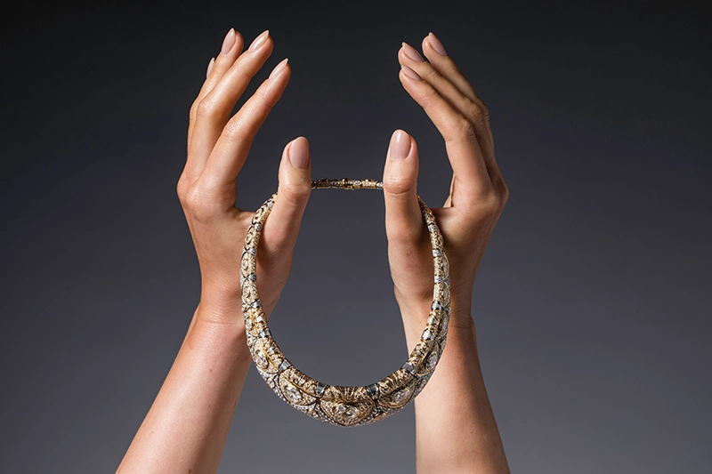 Two hands holding a necklace between the thumbs.