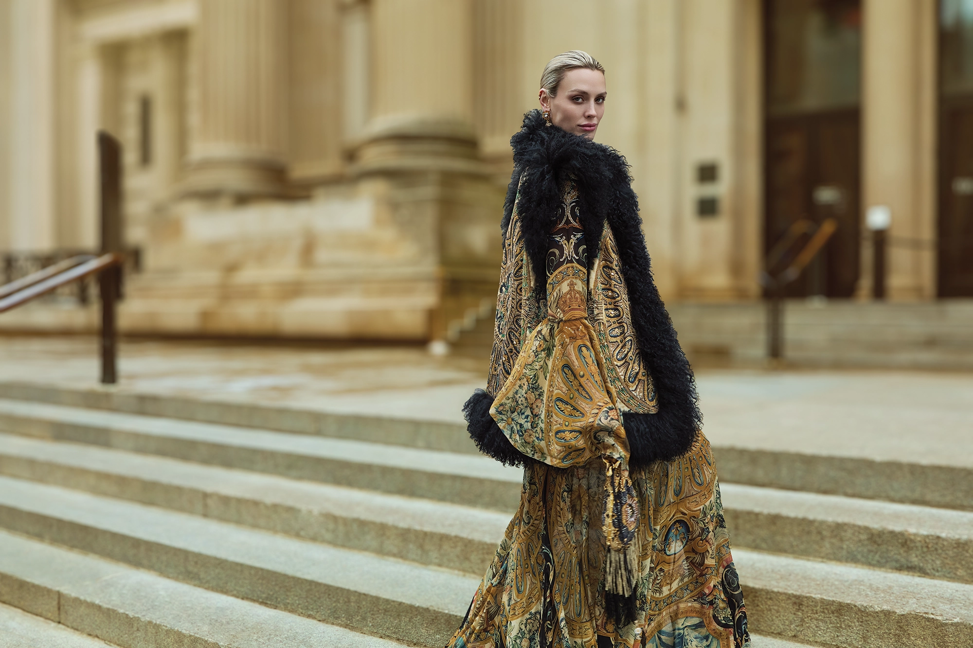 A woman standing on steps wearing an elaborate gown.